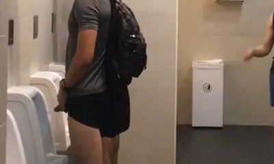 athletic guy caught peeing at urinal