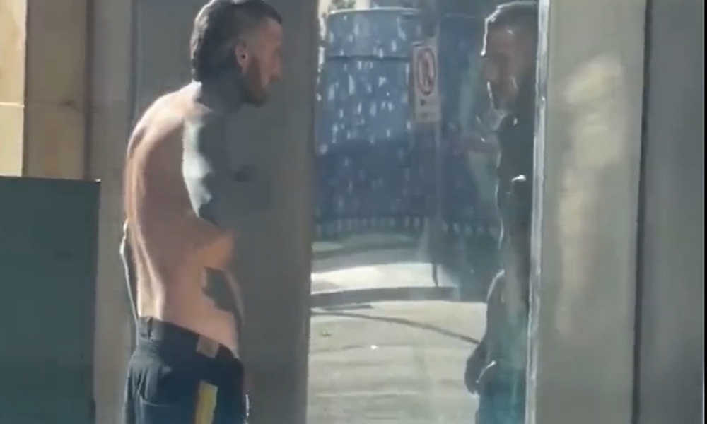 drunk man peeing in public on a glass door
