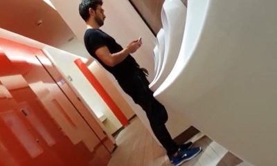 sexy guy dressed in black caught peeing at urinal