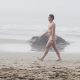 Handsome guy walking naked at the nudist beach