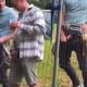 Two friends caught peeing in public behind a fence
