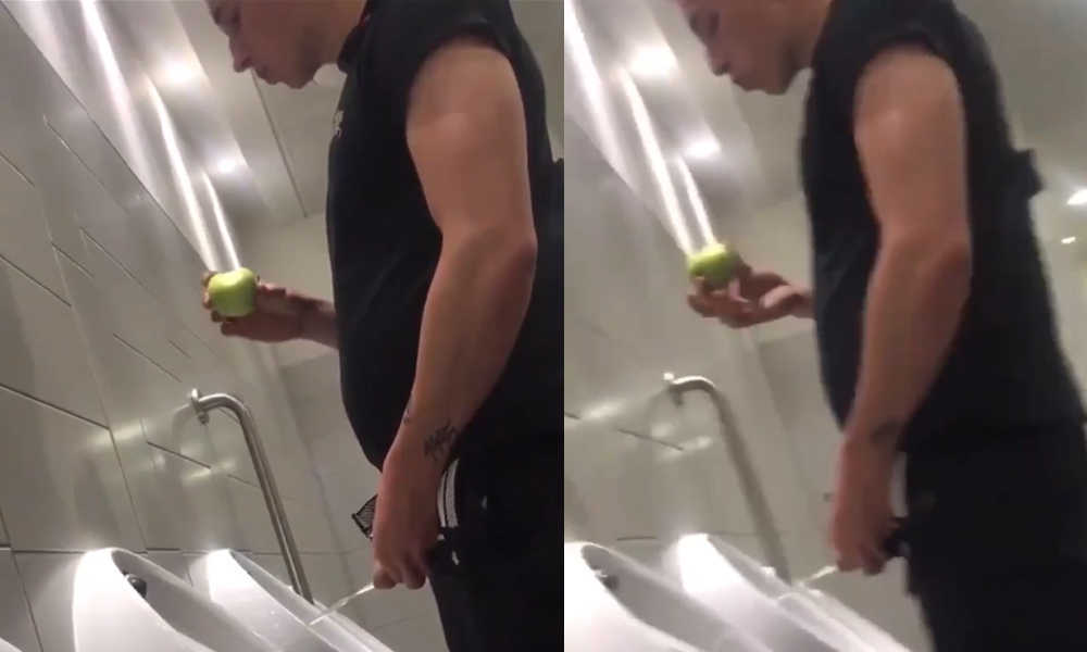 guy peeing at urinal while eating apple